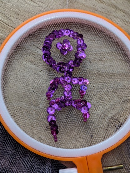 An Einstürzende Neubauten stick man embroidered on white tulle in fuchsia sequins. 