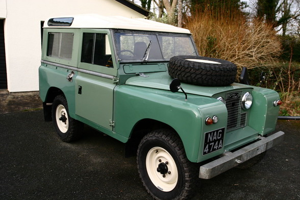 A front three quarters view of a 1961 Series IIA Land Rover. The bulkhead, bonnet, doors, wing fronts and rear side panels are period-correct Pastel Green. The other greens are a bit of a dice-roll. Who said paint uniformity was a good thing?