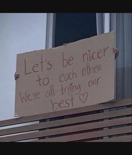 Someone is holding a signboard that says "Let's be nicer to each other, we are all trying our best ❤️