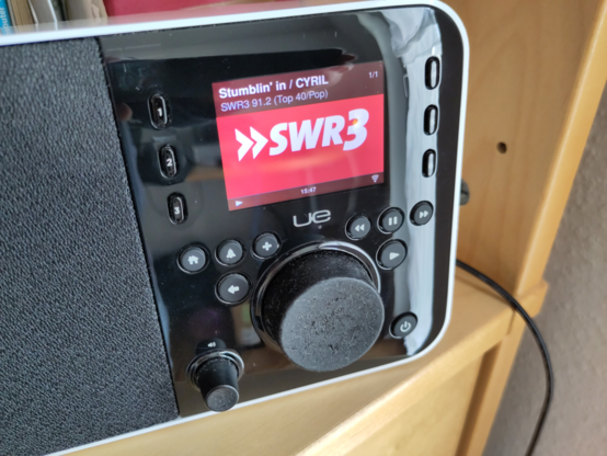 Foto des Bedienfeldes eines Logitech UE Smart Radios. Das Display zeigt das SWR3-Logo an. Der große Drehknopf sieht mitgenommen aus.