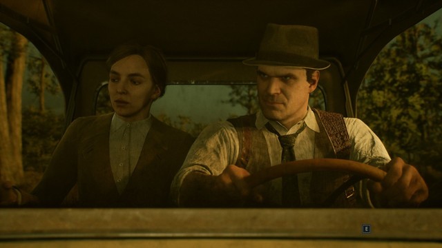 Screenshot from "Alone in the Dark (2024)": Emily Hartwood (Jodie Comer, gray shirt and dark sweater jacket) and Edward Carnby (David Harbour, white shirt, black tie, brown vest and gray fedora) drive to their destination. A bayou with swamp trees  can bevseen through the car and rear windows.