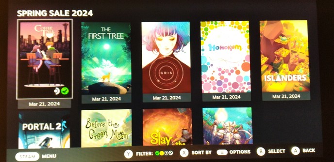 Photo of a Steam Deck library screen, with a collection titled Spring Sale 2024. Game icons in rows. Visible: Coffee Talk, two people seated at a bar; The first tree, a small orange fox under a green night sky; Gris, tearful woman's face over concentric rings or orbits; Hohokum, rainbow of bubbles; Islanders, autumnal landscape with buildings on cliffs.