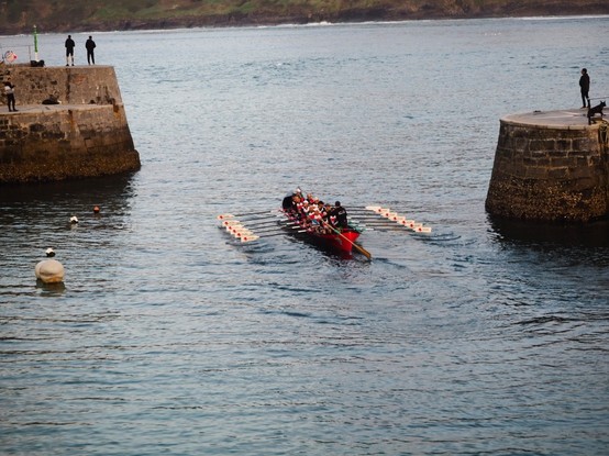 Trece remeros y el patrón de una trainera saliendo del embarcadero de Mundaka.