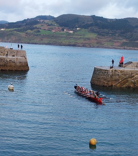 Trece remeros y el patrón de una trainera saliendo del embarcadero de Mundaka