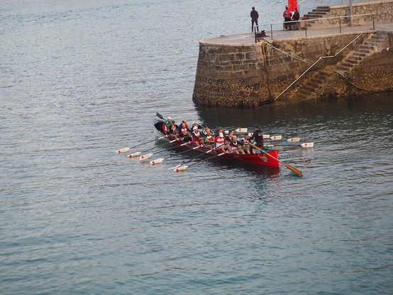 Trece remeros y el patrón de una trainera saliendo del embarcadero de Mundaka