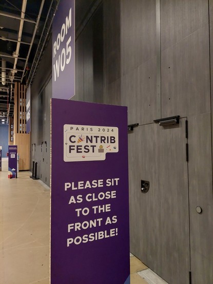 Sign outside of a conference room stating "Contribfest (Please sit as close to the front as possible!)"