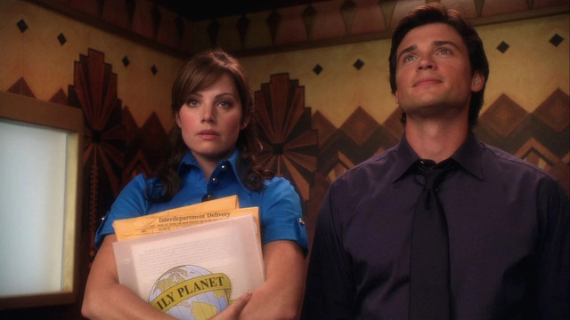 Photo of the characters Lois Lane, on the left, and Clark Kent, on the right, standing in the elevator of the Daily Planet. From Smallville, season eight. 