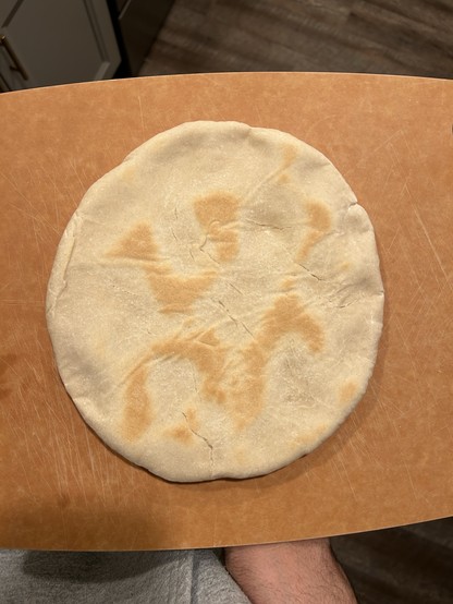 A round shortcake, one that looks similar to naan, sitting on a brown cutting board. 