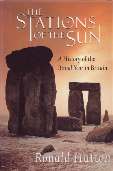 The front cover of The Stations of the Sun: A History of the Ritual Year in Britain by Ronald Hutton, featuring a full-cover colour photo of part of Stonehenge, with a light dusting of snow on the deck and a peachy-coloured sky.