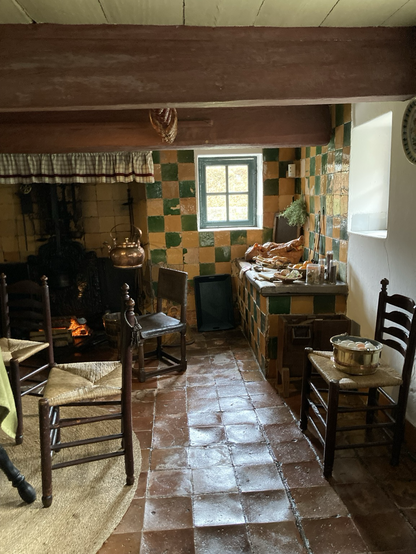 Andere keukenhoek bij de kachel en een werkplek bij het raam 