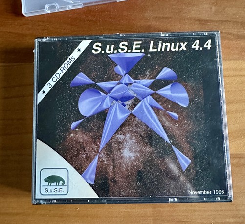 Eine Kunststoffbox, angeschrieben mit
S.U.S.E. Linux 4.4
Eine Computergrafik vor einem Sternenfoto. Unten Links das Chamäleon des Logos der Firma.
Unten Links, das Ausgabedatum: November 1996