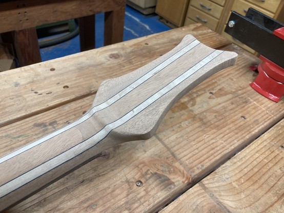 A guitar headstock is shown up close from the back.