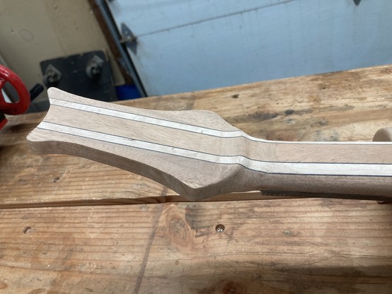 A guitar headstock is shown up close from the back.