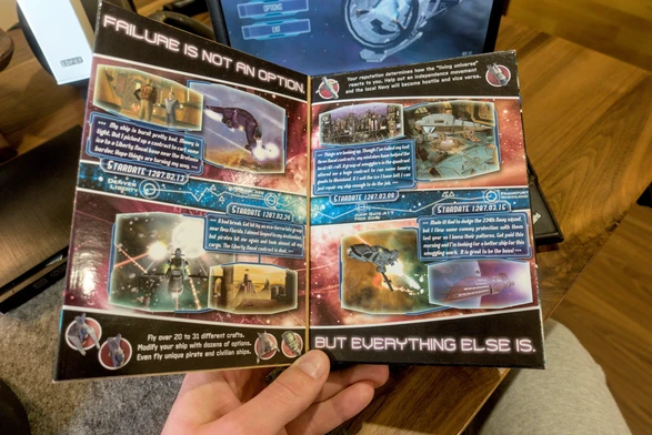 Photo of the opened "gatefold" cover of the physical game box, which shows game screenshots and text blurbs that read like personal diary entries from the in-game protagonist. At the top of the left pane it reads "Failure is not an option." At the bottom of the right pane it continues "But everything else is." The text blurbs are: Stardate 1287.02.13: "My ship is burnt pretty bad. Money is tight. But I picked up a contract to cart some ice to a Liverty Naval base near the Bretonia border. Hope things are turning my way." Stardate 1287.02.24: "A bad break. Got hit by an eco-terrorists group near New Florida. I almost limped to my destination, but pirates hit me again and took almost all my cargo. The Liberty Naval contract is dust." Stardate 1287.03.09: "Things are looking up. Though I've failed my last three Naval contracts, my mistakes have helped the local riff-raff. A group of smugglers in the quadrant offered me a huge contract to run some luxury goods to Rheinland. If I sell the ice I have left I can just repair my ship enough to do the job." Stardate 1287.03.15: "MAde it! Had to dodge the 234th Navy squad, but I flew some convoy protection with them last year so I knew their patterns. Got paid this morning and I'm looking for a better ship for this smuggling work. It is great to be the boss!" Additional text: Your reputation determines how the "living universe" reacts to you. Help out an independence movement and the local Navy will become hostile and vice versa.