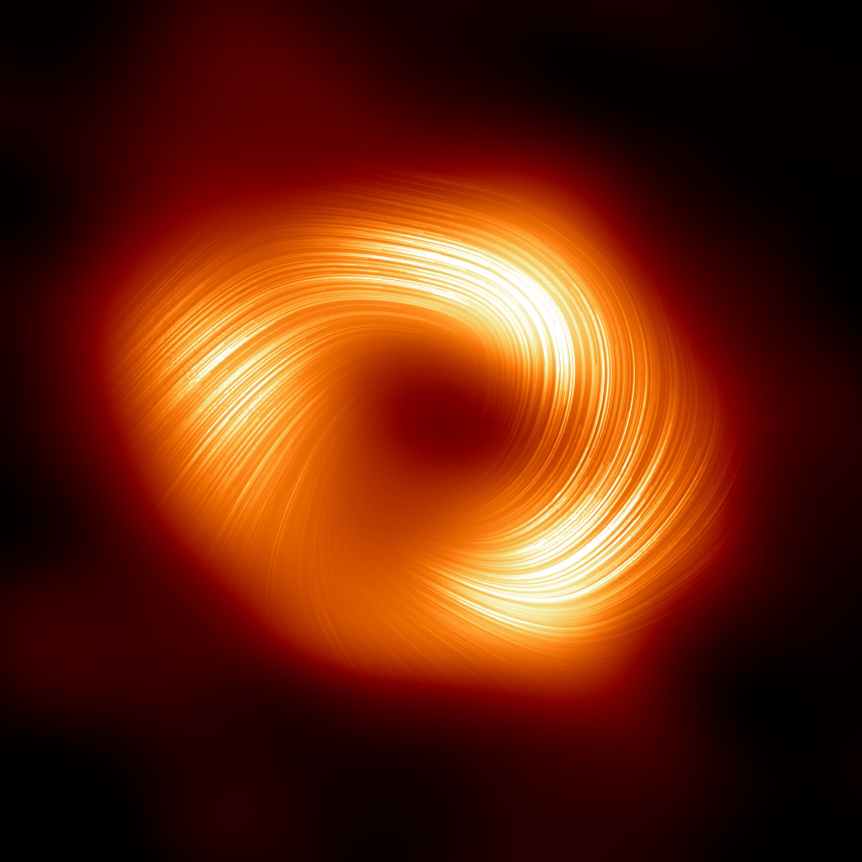 Image of the supermassive black hole in the Galactic Center. An orange ring with three bright regions and hair-like structures. The orange color shows total intensity of the mm-wave radio emission, the fine lines indicate polarization direction. Magnetic fields are typically at right angle to those lines. Credit: Event Horizon Telescope 2024 