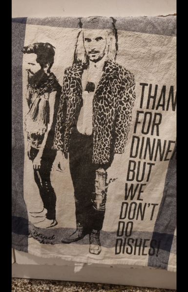A white and grey  towel with/from the Swiss two-piece "Blind Butcher" saying "Thanks for dinner but we don't do dishes"