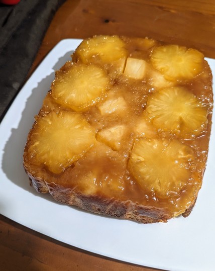 Pineapple cake turned out onto a rectangular white plate. The syrup and fruit on top are nicely browned.