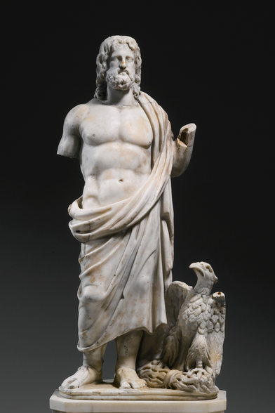 Marble statue of Zeus-Jupiter as a mature, bearded god with shoulder-length hair. He is dressed in a himation draped over his shoulder and around his lower body, leaving his torso bare. An eagle perches at his feet.