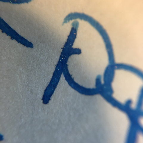 close up shot of previous writing sample showing gold 'speckle' in dried ink. 