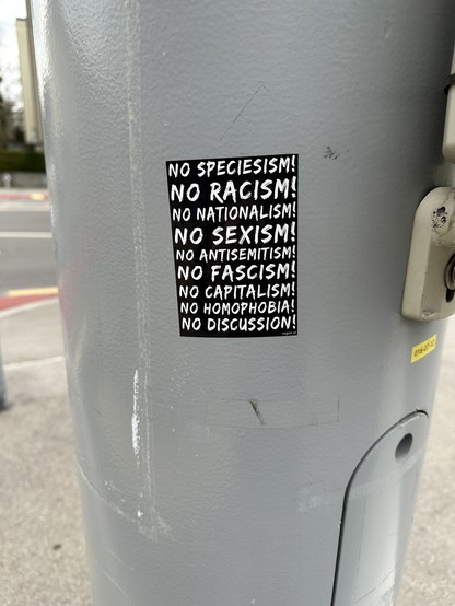 Sticker on a pole saying:
No spiecisism!
No racism!
No nationalism!
No sexism!
No antisemitism!
No facism!
No capitalism!
No Homophobia!
No discussion!
