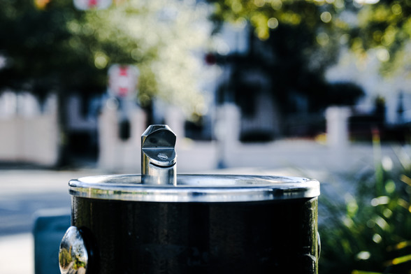 A close up water fountain near Colonial Lake in Charleston SC with a blurred background showing the nearby street and houses
