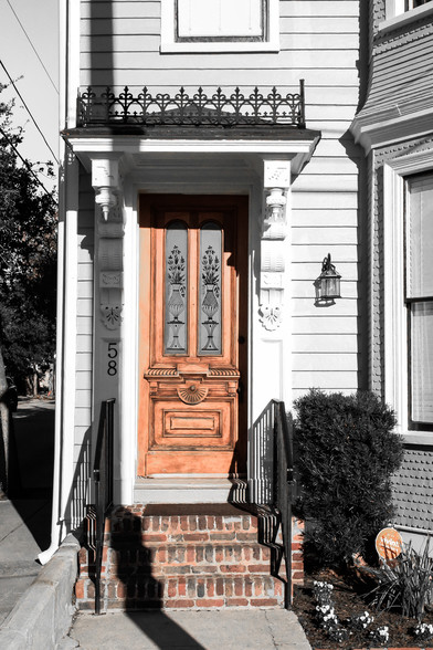 A mostly black and white picture showing a narrow door at a historical home on Colonial Lake in Charleston SC.  The door and steps leading to it show their actual color.  