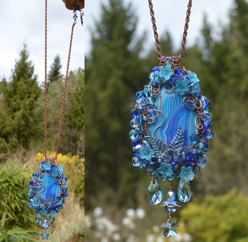 A vivid blue pendant, hanging from it's chain against a green garden backdrop. The left photo shows the whole necklace, the right photo a close up of the pendant details. The central stone is oval, and framed with a thick ring of woven beads and copper wire. Underneath are 3 light blue clear Swarovski crystal pendants, their facets reflecting the light.
