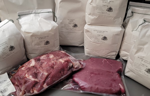 Farbfoto: Die eingekaufte Ware - etliche Mehltüten und zwei Päckchen mit Fleisch. 