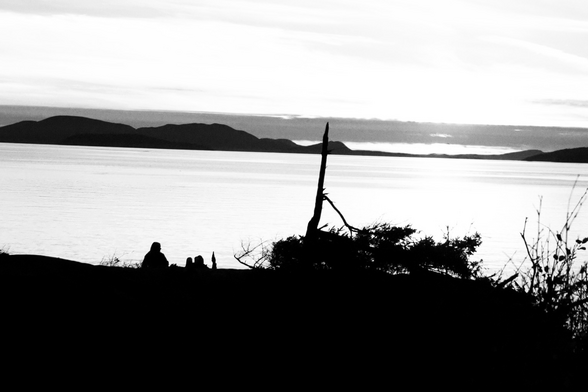Black and white photo depicts couple overlooking the ocean at sunset 