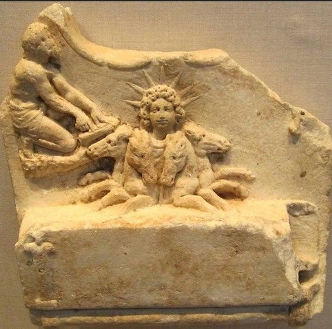Marble relief of Helios emerging from the sea with his chariot drawn by four horses. One can only see his head behind the four heads of his steeds, with curly hair and a seven-spiked sunray crown.