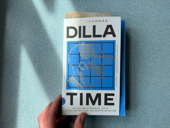 Cover of the book Dilla Time. Subtitle reads: The Life and Afterlife of J Dilla, the Hip-Hop Producer Who Reinvented Rhythm. The illustration between the bold letters shows a stylized portrait of the producer composed of little golden squares. Below a 4 by 4 grid that reminds of the touch pads of an Akamai MPC sampler/sequencer.