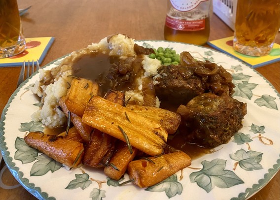 A traditional vegan Easter roast dinner of rosemary & garlic butter roasted carrots, Aldi stuffed faux lamb joint, mash, peas and gravy with added caramelised onions 