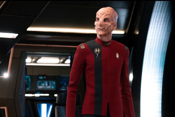 First Officer Saru (Paul Jones) looks sideways (probably at the viewscreen) while standing on what seems to be the bridge of the U.S.S. Discovery.
