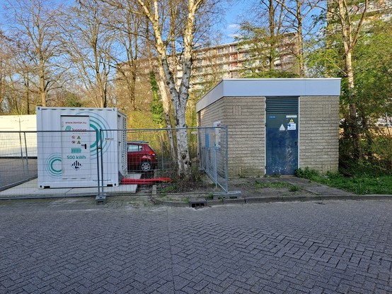 Electriciteitshuisje met daarnaast een kleine witte container die een 500 kWh accu bevat. De accu is ca half zo groot als de trafo.