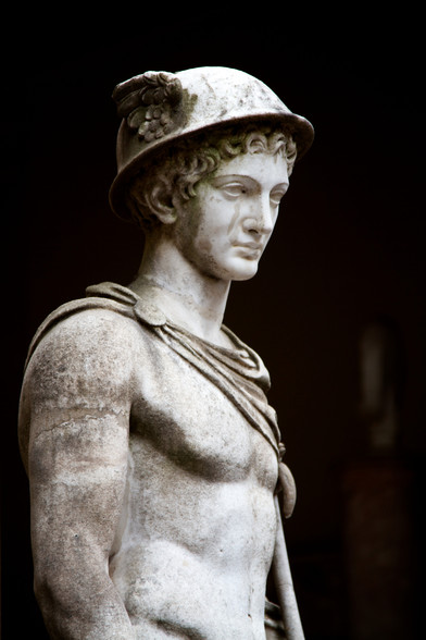 Marble statue of the Roman god Mercurius or Mercury. He is wearing a winged hat on his curly hair and a chlamys cloak pinned above his right shoulder.