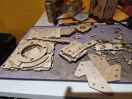 Assorted laser cut pieces spread out on a table, some art visible including etchings of a book, sun, moon, and mountains