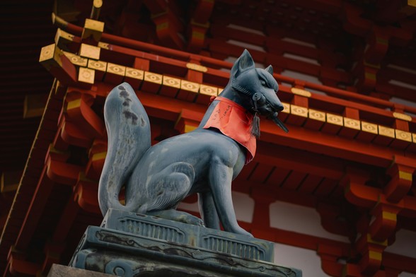 Statue of a fox holding a scroll outside Fushimi Inari-taisha, a Shinto shrine in the Japanese city of Kyoto