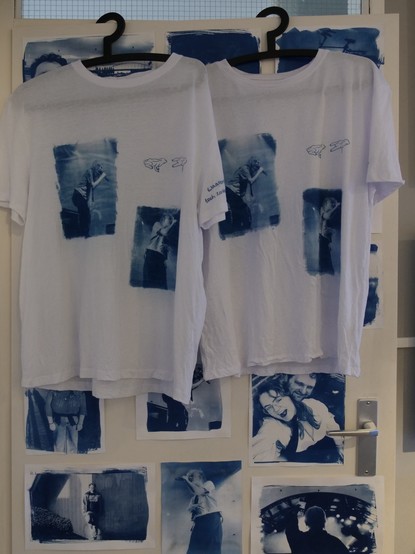 The two shirts on hangers on the living room door with cyanotype pictures on the door

