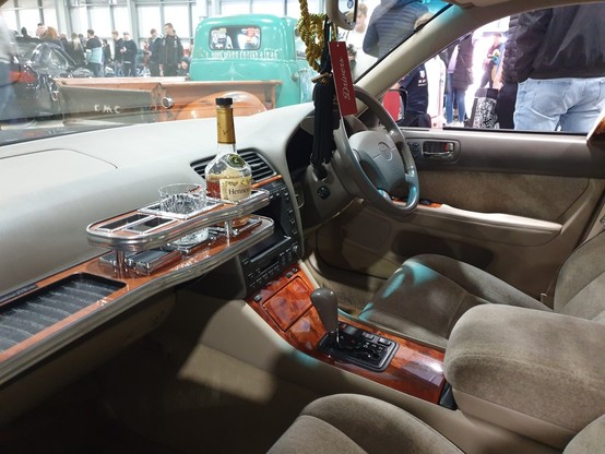 The interior of Toyota Celerion with bottle of cognac and two crystal glasses on a tray mounted to the dashboard.