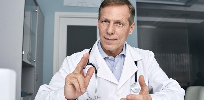 Male doctor points while wearing a white coat and stethoscope