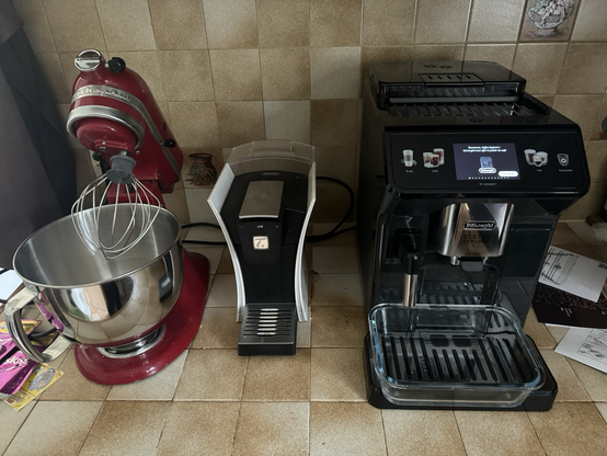 Kitchen countertop with a red KitchenAid stand-mixer, a the machine and a gigantic coffee machine 