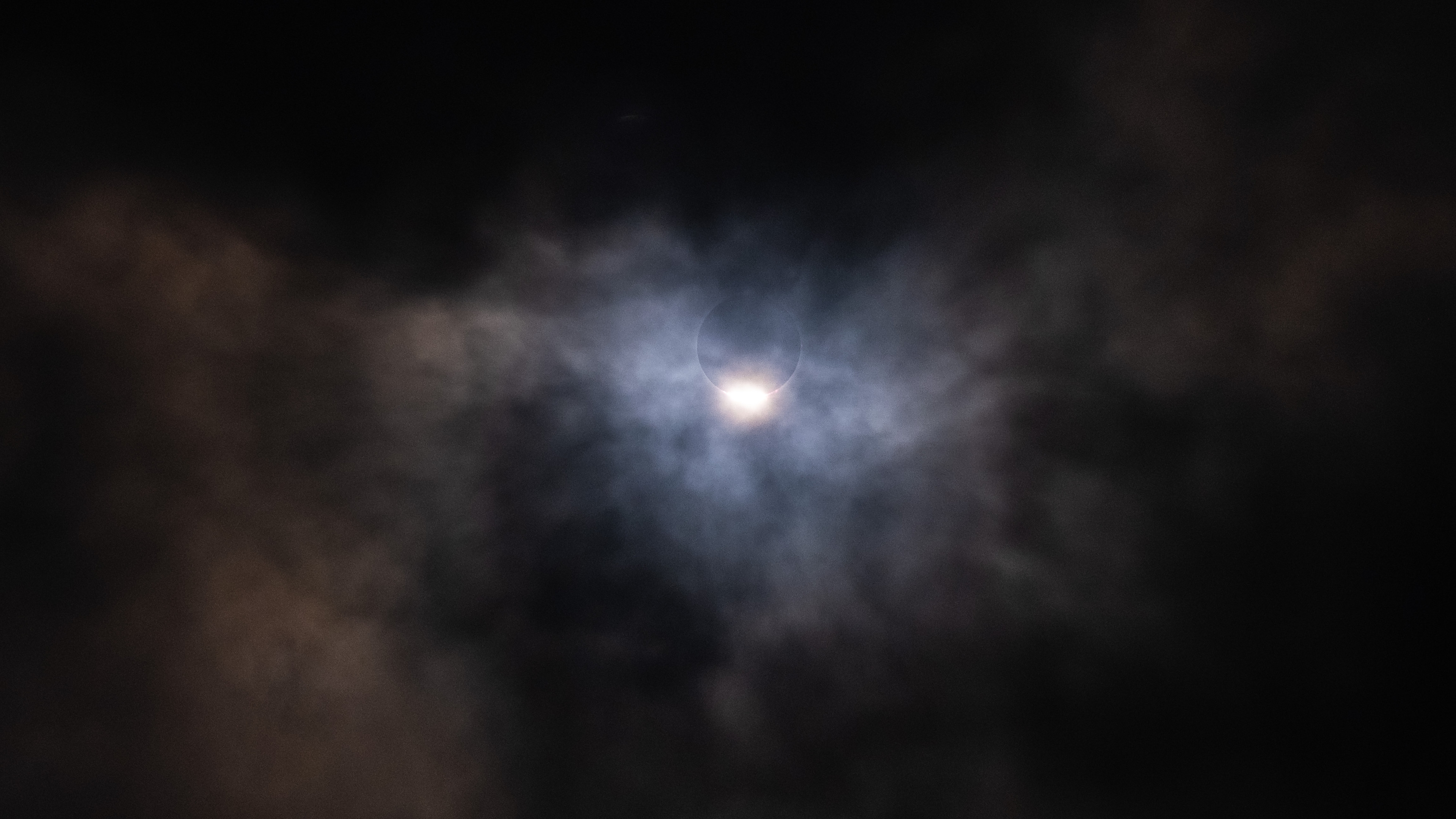 Through a layer of low clouds, the diamond ring of the eclipse shines.