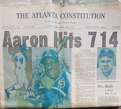 The Atlanta Constitution newspaper, dated April 5, 1974. The bold, simple headline reads "Aaron Hits 714," along with a photo and a drawing of Henry 'Hammering Hank' Aaron and a photo of a sad looking Babe Ruth.
