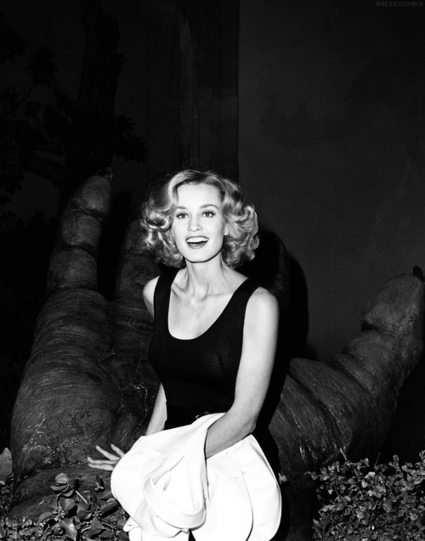 A photo of actress Jessica Lange at a press conference for King Kong (1976). She sits in a replica of the giant gorilla's outstretched palm. 