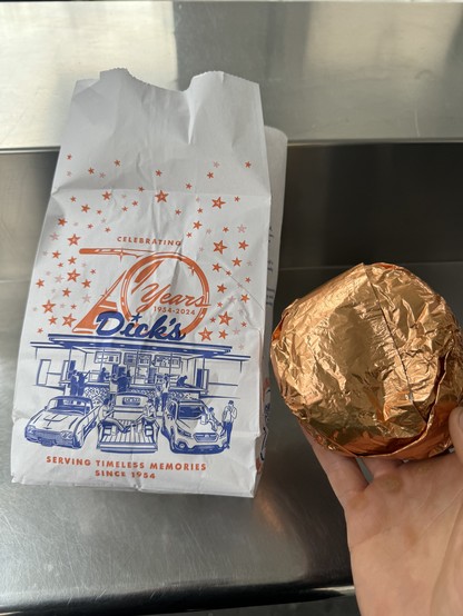 A bag from Dick’s with a Dick’s Deluxe burger next to it.