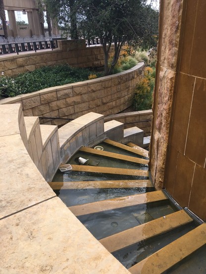 Staircase-like fountain with terraced pools, and planters and staircase behind