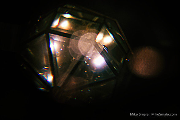 A lamp in my kitchen reflecting in a pair of reading glasses left on the counter at midnight.