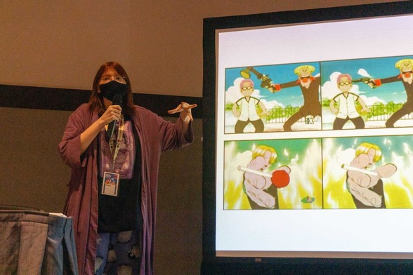 Photo of anime historian Red Bard standing next to a projection of image comparisons between the unedited versions of One Piece and their 4Kids-censored equivalents.