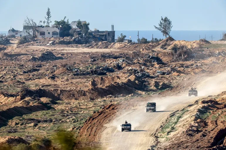 Overturned soil can be seen as Israeli army vehicles drive along a dirt road in the Gaza Strip near the southern Israel border on January 4 [Jack Guez/AFP]