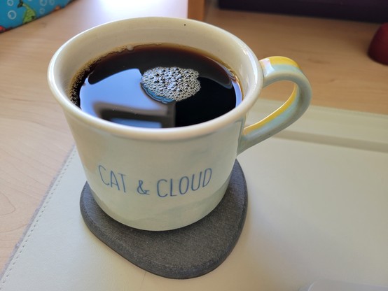 A glazed, hand-thrown 10-ounce light-blue ceramic camp mug with striped light-blue & light-yellow handle and off-white interior, filled with cold-brew coffee, on a gray diatomaceous-earth coaster on an off-white desk mat on a maple desk. 

Dark-blue block letters at center read "Cat & Cloud". 

Artist: Kelly Beach Ceramics

Description (circa March 2020)

"Limited Run : Unlimited Fun
Two moods, one mug. Hand thrown and painted by our very own, Kelly Beach! While the two tone design was originally just the color test, we decided to rock it cause it's - you know it - the best of both worlds!
Kelly earned her BFA at San Jose State, focusing on ceramics. This camp mug shape has been in her wheelhouse (pun intended) for a minute! It just so happens that she first sold her work at a Cat & Cloud pop-up in 2018...she also met her fiancé that day, no big deal. 
This multi-talented gal is busy being a ballerina teacher and won't have more time to throw more until summer - only 25 of these guys, so don't sleep!
Kelly Beach Ceramics feature a geometric, tight style. You can check our more of her work here!
Online exclusive!"